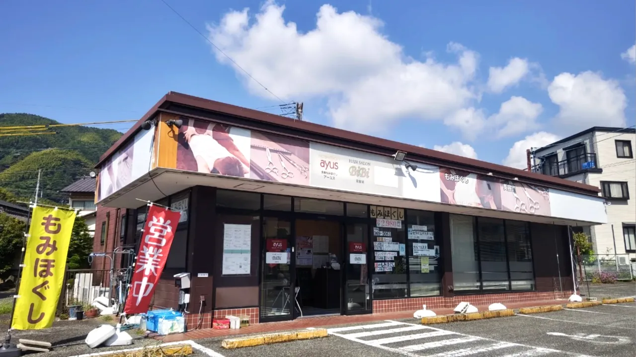 国道52号線沿いに立つ全身もみほぐしアーユスの外観。「もみほぐし」ののぼりと、店の前の無料駐車場